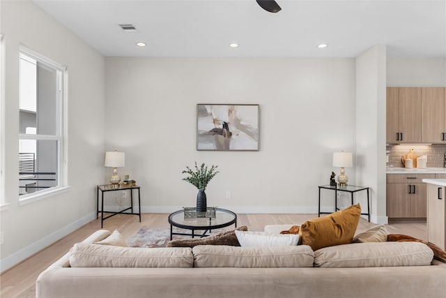 living area with a wealth of natural light, visible vents, baseboards, and light wood finished floors