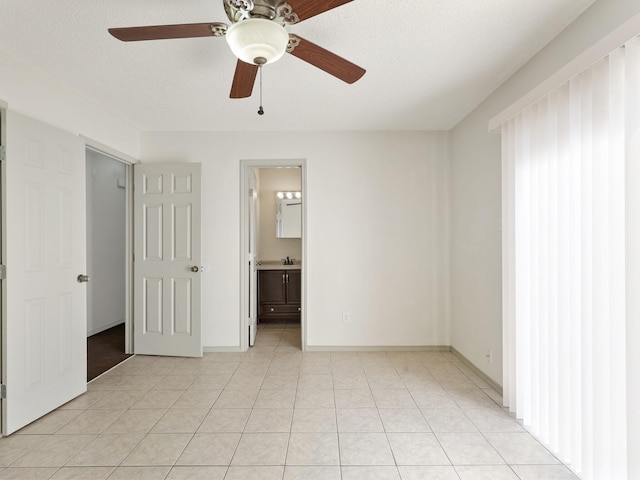 unfurnished bedroom with a ceiling fan, ensuite bathroom, a textured ceiling, light tile patterned floors, and baseboards