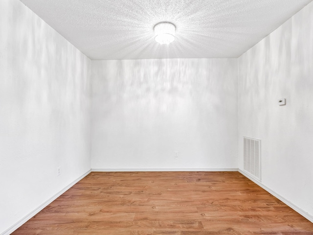 spare room with visible vents, a textured ceiling, and light wood-type flooring