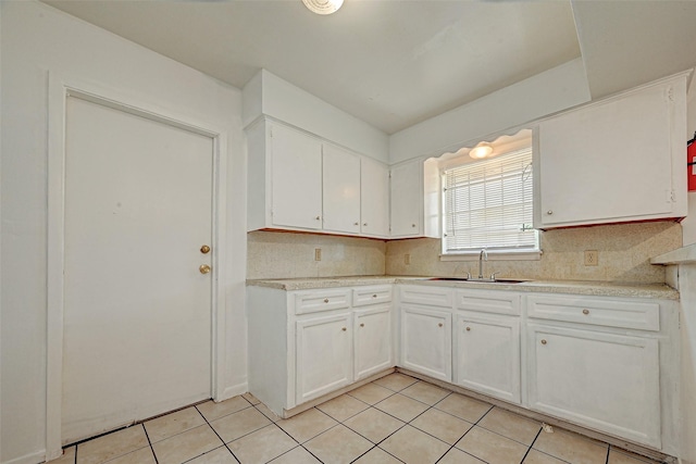 kitchen with light countertops, white cabinets, light tile patterned floors, and a sink