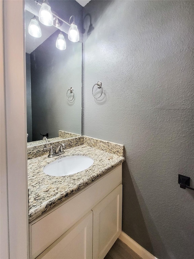 bathroom featuring baseboards, vanity, and a textured wall