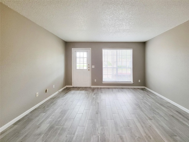 spare room with a textured ceiling, baseboards, and wood finished floors