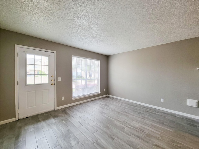 doorway to outside with baseboards, wood finished floors, and a textured ceiling