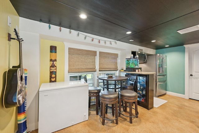 interior space with bar area, baseboards, light colored carpet, recessed lighting, and rail lighting