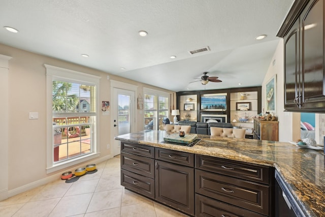 kitchen featuring dark stone countertops, light tile patterned flooring, a ceiling fan, and visible vents