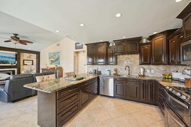 kitchen featuring a sink, stone countertops, open floor plan, appliances with stainless steel finishes, and ceiling fan