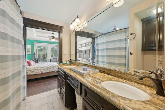 ensuite bathroom with tile patterned flooring, ceiling fan, double vanity, ensuite bath, and a sink