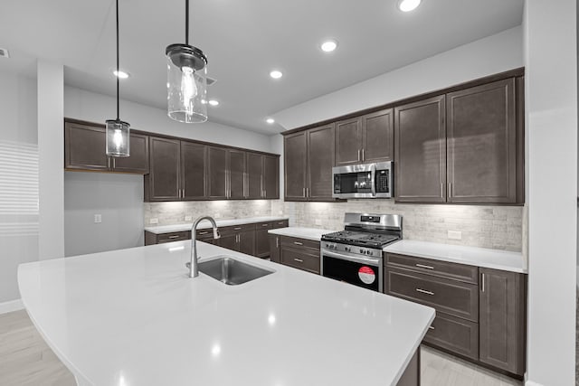 kitchen with a sink, decorative backsplash, light countertops, dark brown cabinets, and appliances with stainless steel finishes
