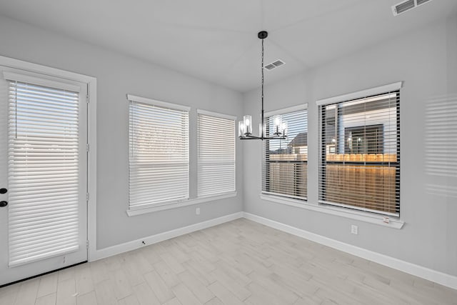 unfurnished dining area featuring visible vents, baseboards, an inviting chandelier, and wood finished floors