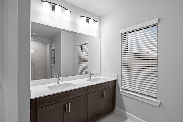 full bath with a sink, baseboards, double vanity, and tile patterned flooring