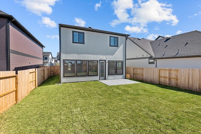 rear view of house featuring a lawn and a fenced backyard
