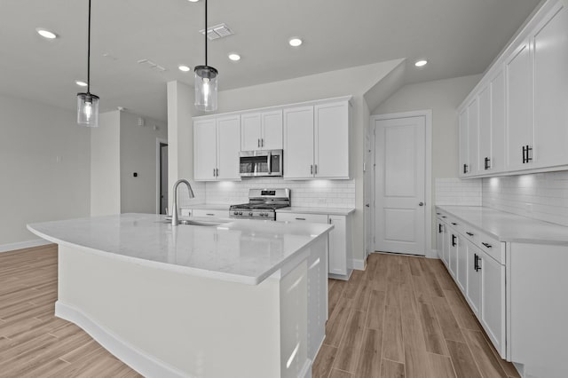 kitchen with visible vents, wood finish floors, a sink, appliances with stainless steel finishes, and white cabinetry