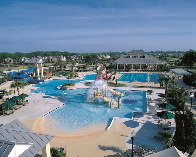 pool featuring a water slide, a water play area, and a patio
