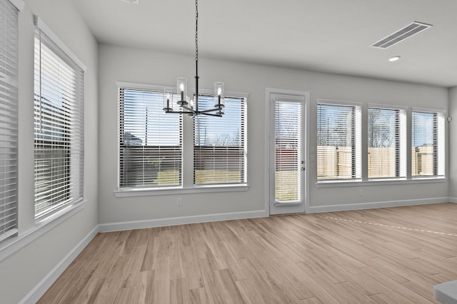 unfurnished dining area with a notable chandelier, visible vents, light wood-style flooring, and a wealth of natural light