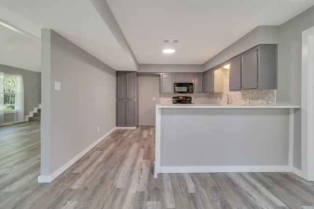 71 Deer Run Cir, Coldspring, TX 77331 - kitchen with black appliances, gray cabinets, light wood finished floors, light countertops, and decorative backsplash