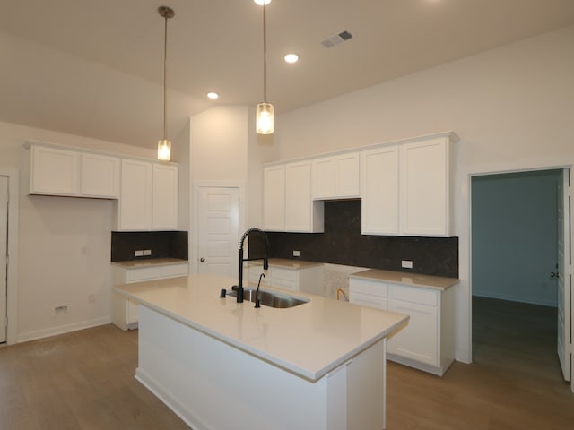 8634 Sun Coral Dr, Cypress, TX 77433 - kitchen featuring white cabinetry, decorative backsplash, a center island with sink, light wood-style floors, and decorative light fixtures