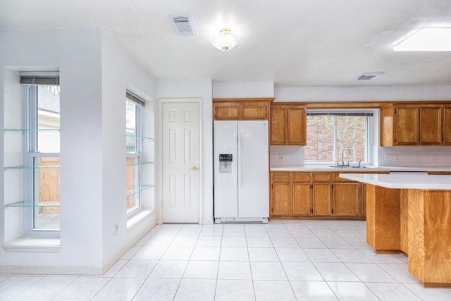 kitchen with light countertops, brown cabinetry, visible vents, and white fridge with ice dispenser