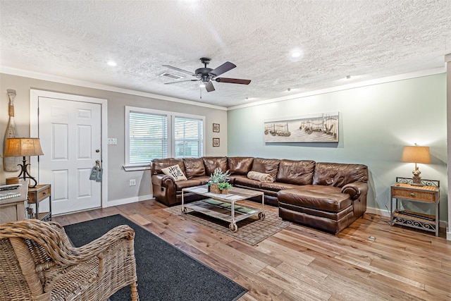 living area with visible vents, ornamental molding, ceiling fan, and wood finished floors