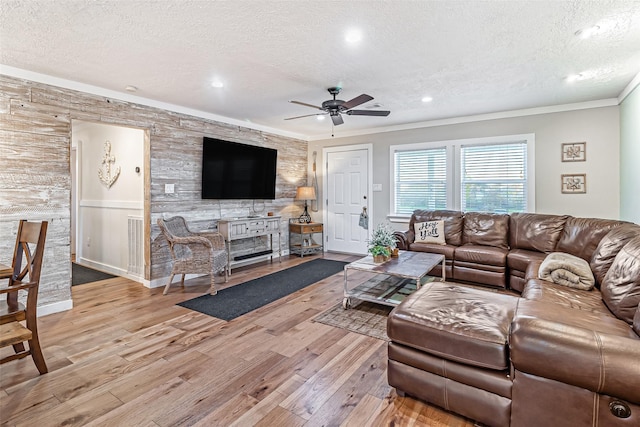 living area featuring ornamental molding, a textured ceiling, ceiling fan, and wood finished floors