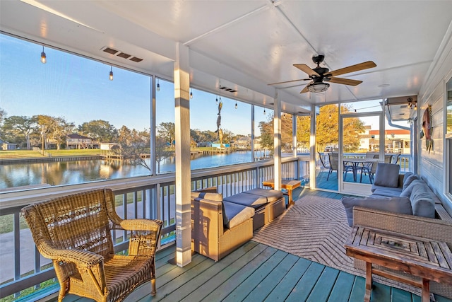 sunroom featuring visible vents, a water view, and ceiling fan