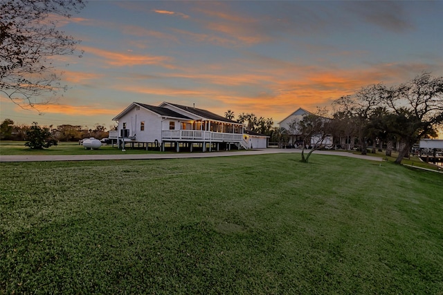 rear view of house with a yard, a wooden deck, and concrete driveway
