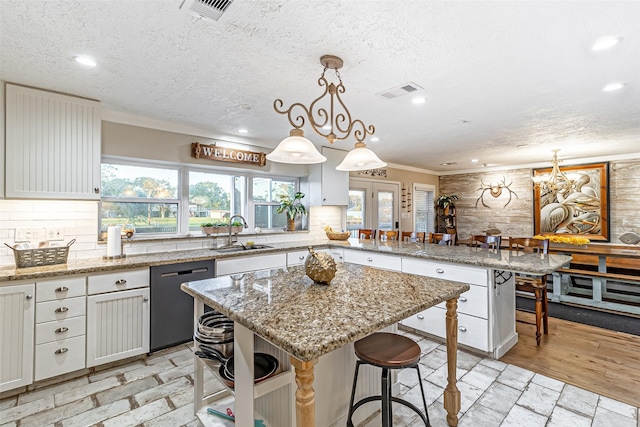 kitchen featuring dishwasher, decorative backsplash, visible vents, and a sink