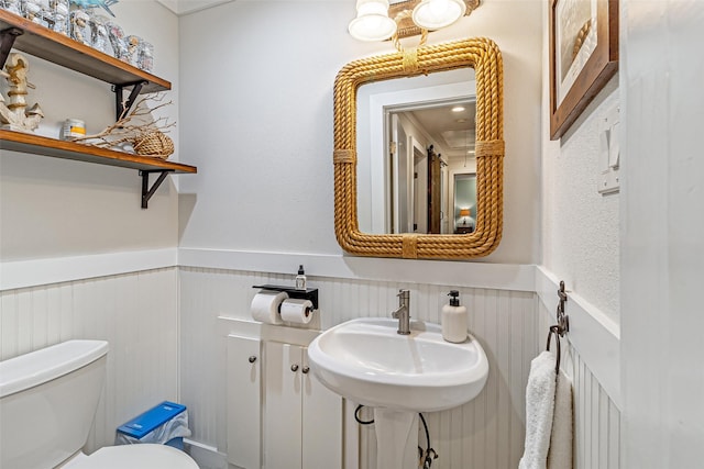 bathroom with wainscoting, toilet, and a sink
