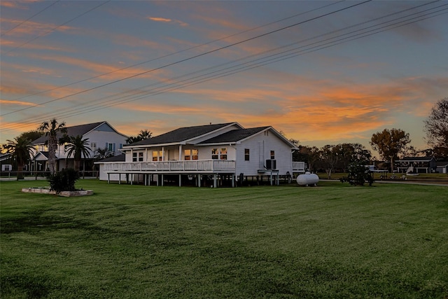 back of house at dusk with a lawn and a deck