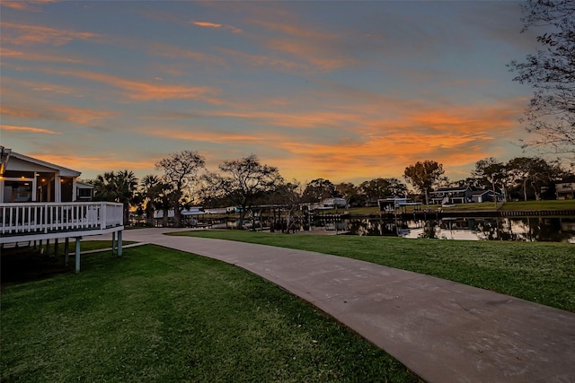 view of community with a water view, a lawn, and a dock