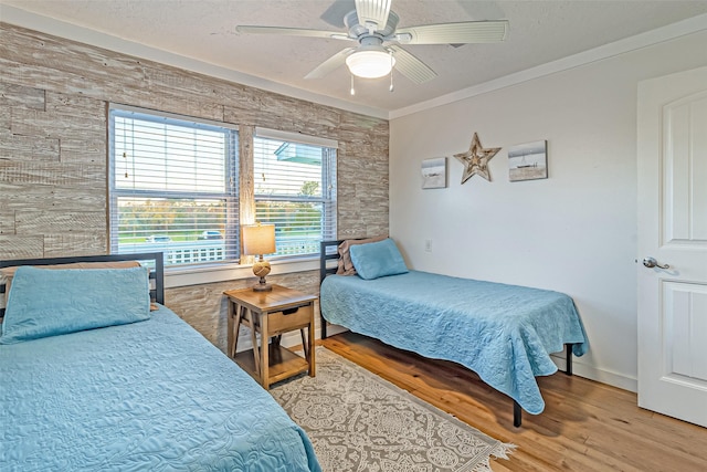 bedroom with light wood-style flooring, a textured ceiling, crown molding, and ceiling fan