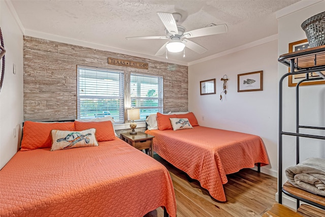 bedroom with ceiling fan, a textured ceiling, crown molding, and light wood-style floors