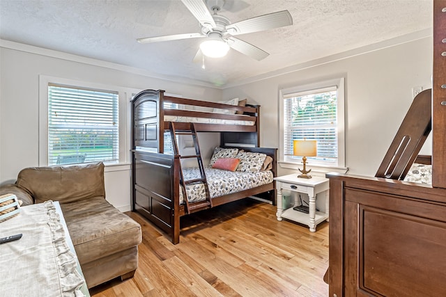 bedroom with light wood-style flooring, a ceiling fan, and a textured ceiling