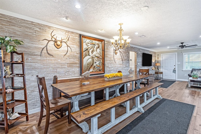 dining space with baseboards, recessed lighting, ceiling fan with notable chandelier, wood finished floors, and a textured ceiling