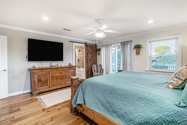 bedroom with light wood-type flooring, a barn door, multiple windows, and crown molding