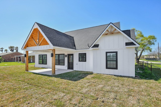 back of property featuring board and batten siding, fence, roof with shingles, a lawn, and a patio
