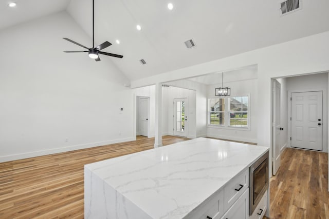 kitchen featuring stainless steel microwave, light wood-style flooring, and visible vents
