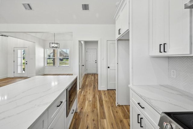 kitchen with decorative backsplash, an inviting chandelier, visible vents, and light wood finished floors