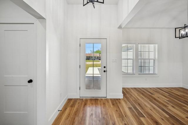 entryway with baseboards, an inviting chandelier, and wood finished floors