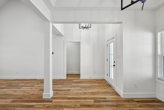 foyer entrance featuring an inviting chandelier, light wood-style flooring, and baseboards