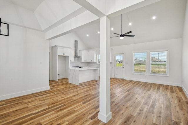 unfurnished living room with baseboards, light wood-style flooring, high vaulted ceiling, and ceiling fan