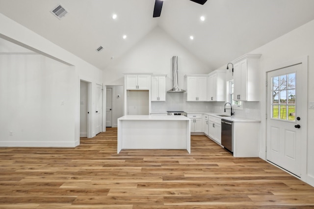 kitchen with visible vents, a kitchen island, stainless steel appliances, wall chimney range hood, and ceiling fan
