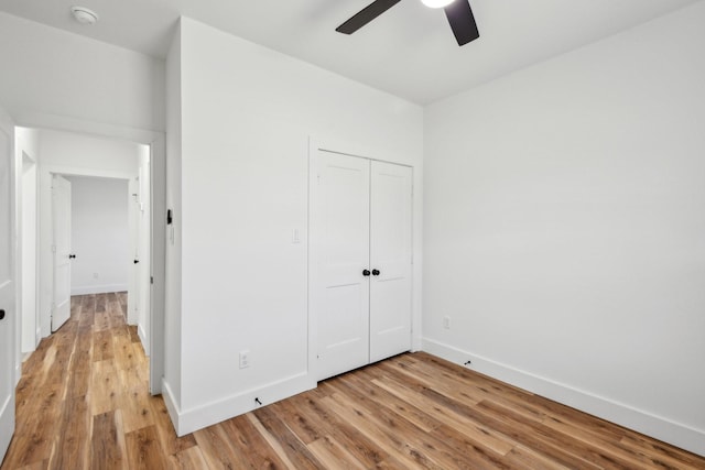 unfurnished bedroom with a closet, baseboards, and light wood-style floors