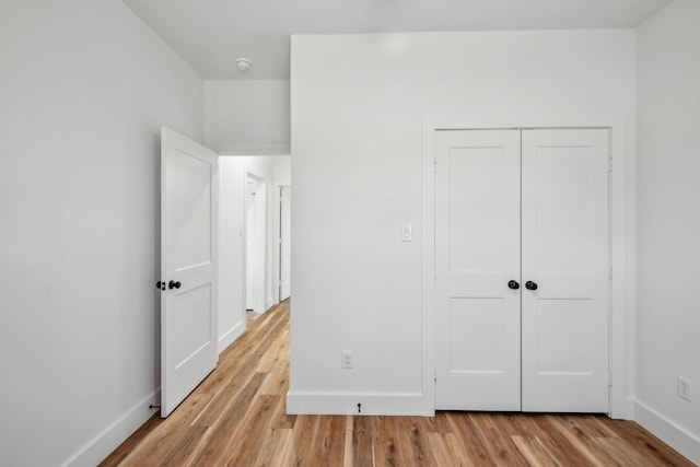 unfurnished bedroom featuring baseboards, a closet, and light wood finished floors