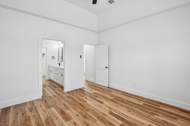 unfurnished bedroom featuring a high ceiling, light wood-style flooring, visible vents, and baseboards
