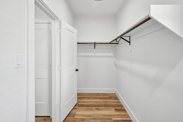 walk in closet with light wood finished floors