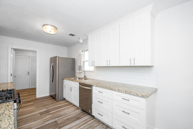 89 Bayou Ln, Kemah, TX 77565 - kitchen featuring appliances with stainless steel finishes, backsplash, white cabinets, and light wood-type flooring