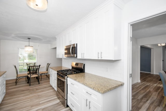 89 Bayou Ln, Kemah, TX 77565 - kitchen featuring stainless steel appliances, decorative backsplash, white cabinetry, light wood-style floors, and light stone counters