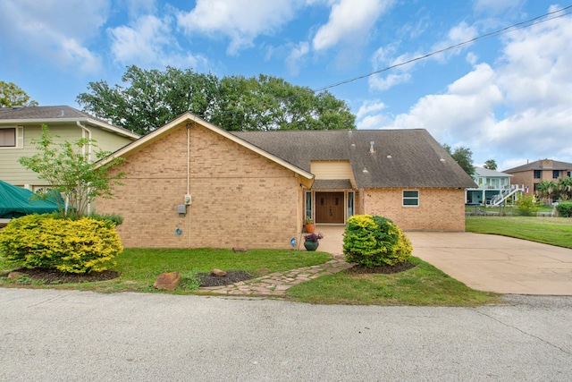 89 Bayou Ln, Kemah, TX 77565 - view of front of home featuring brick siding, concrete driveway, a front lawn, and a shingled roof
