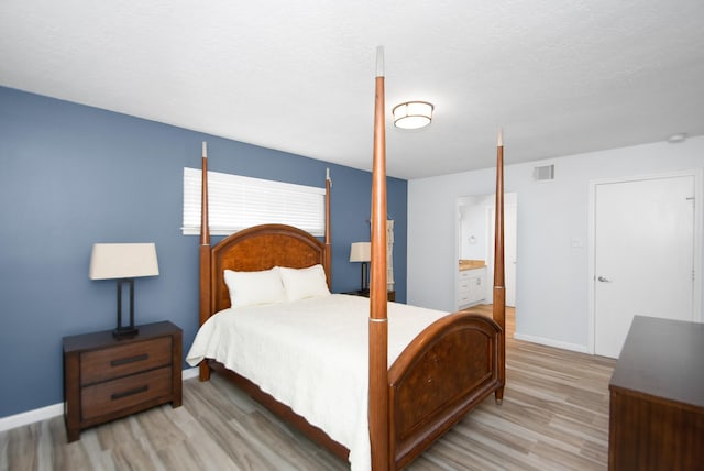 89 Bayou Ln, Kemah, TX 77565 - bedroom featuring light wood-style floors, ensuite bath, and a textured ceiling