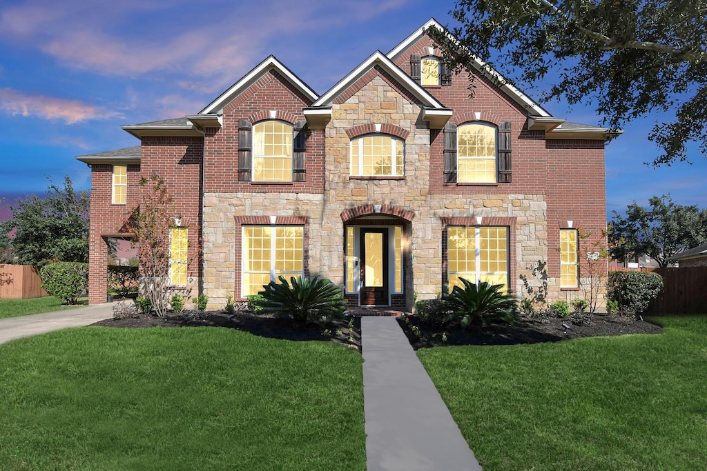 17026 N Aliana Rd, Richmond, TX 77407 - view of front of home with stone siding, brick siding, a front yard, and fence